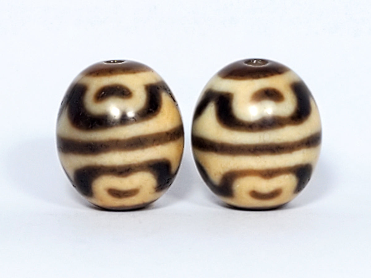 Pair of round tiger tooth and lotus dzi beads with cream and brown agate patterns, drilled holes visible
