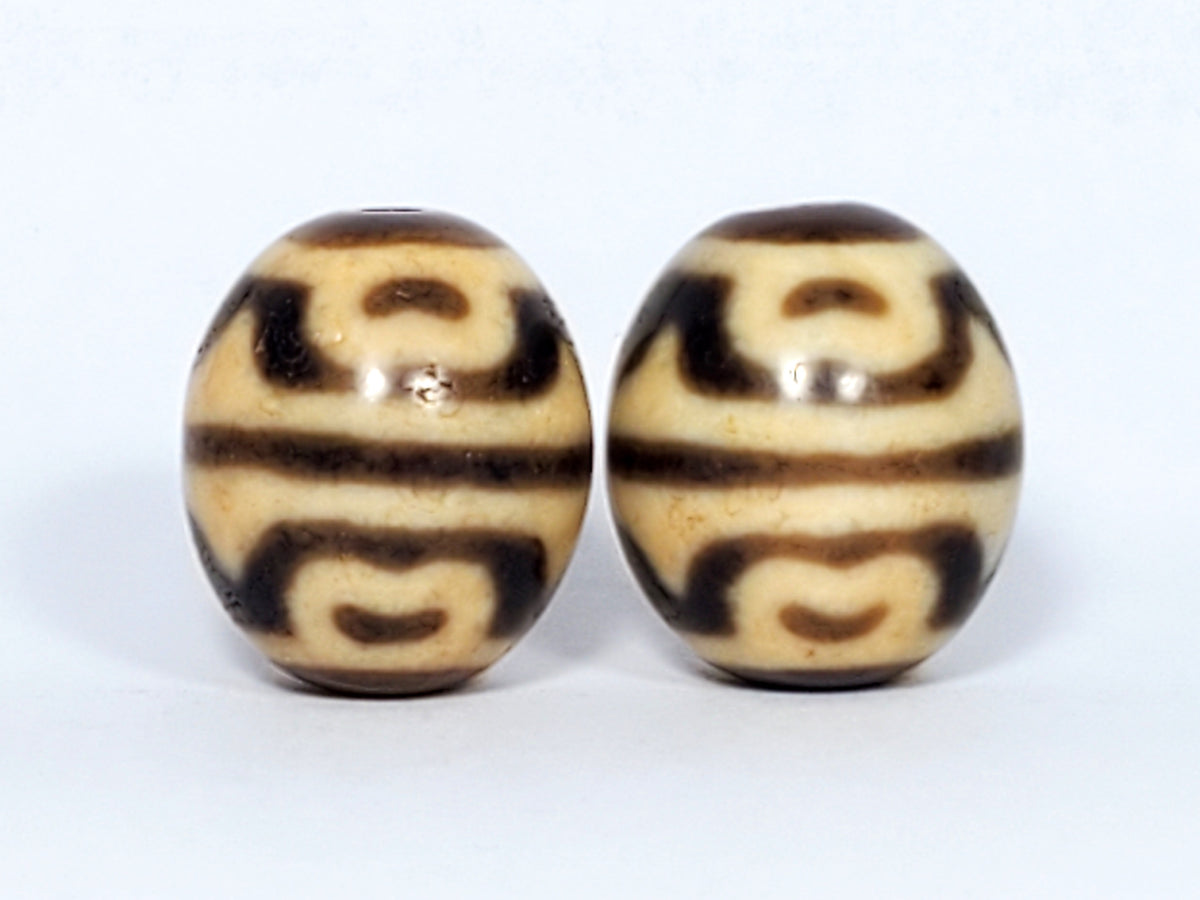 Pair of round tiger tooth and lotus dzi beads with cream and brown agate banding, polished surface