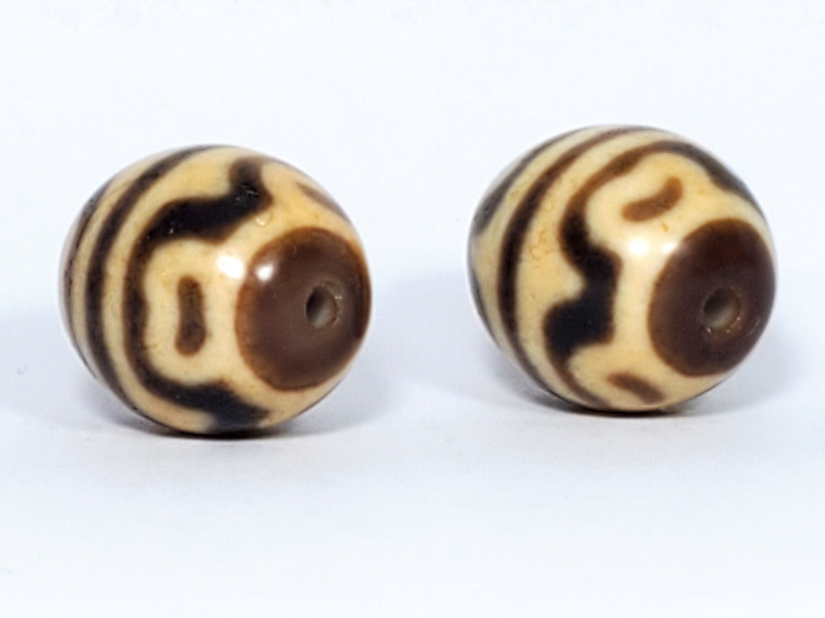 Pair of round tiger tooth and lotus Dzi beads with cream and brown agate banding and central drill holes
