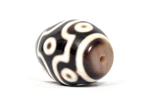 Rare nine-eye Tibetan dzi bead with cream and black agate patterns, visible drill hole, and natural bloodspots