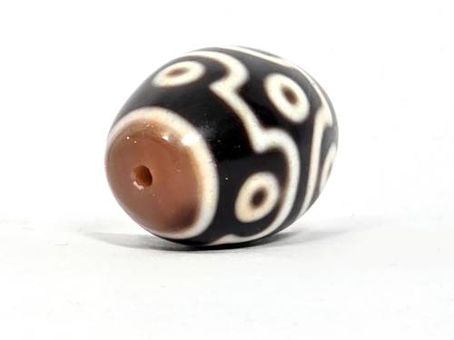 Rare nine-eye Tibetan dzi bead with black agate, cream patterns, brown bloodspots, and visible drill hole