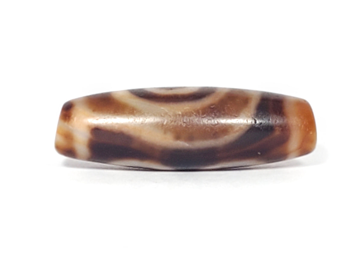 Antique three-eye dzi bead, brown agate with cream eye motifs, aged patina, elongated barrel shape, visible wear