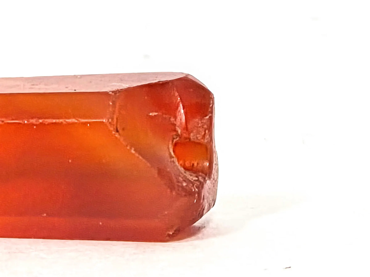 Ancient Indus Valley beveled carnelian bead, translucent orange-red agate, visible drill hole, surface chipping, 28mm elongated barrel