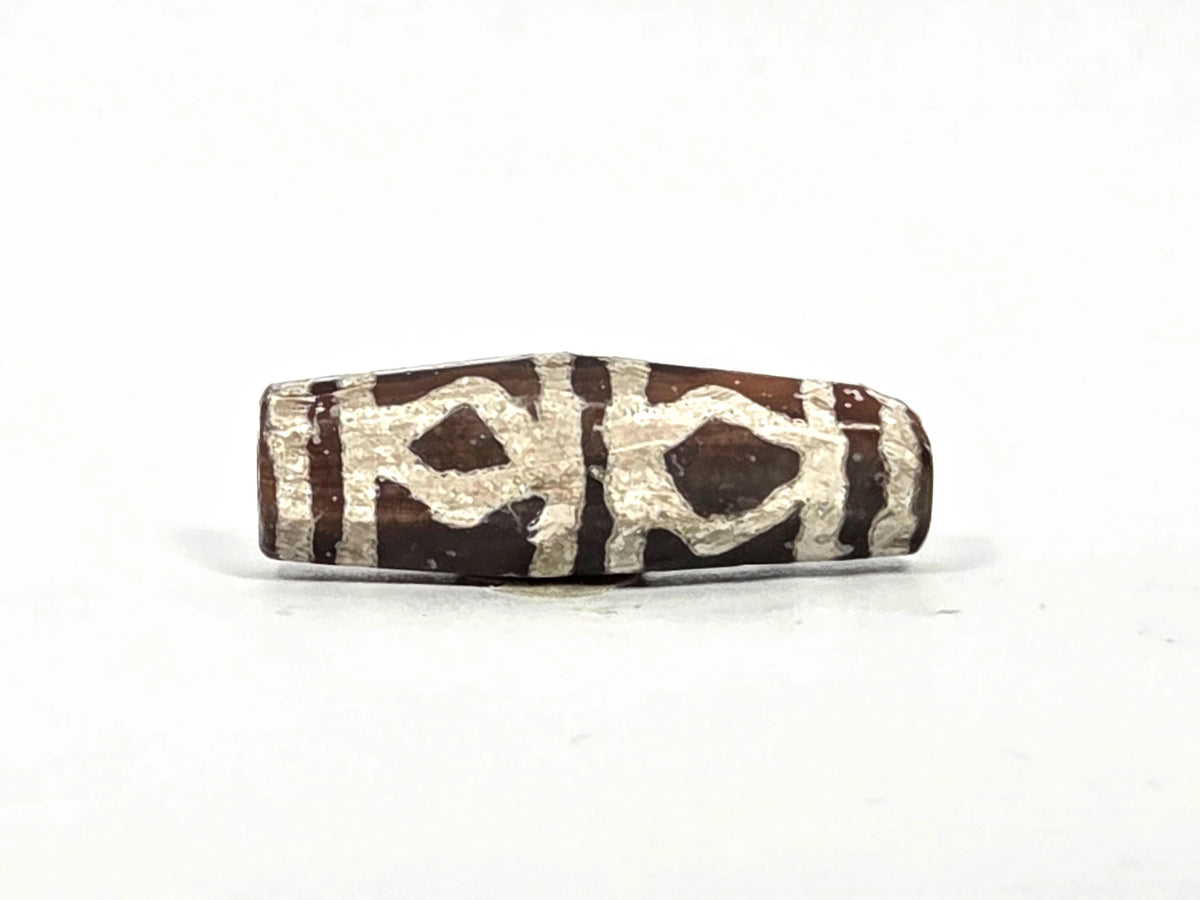 Third lateral profile of ancient etched carnelian bead AC-101226-EC showing diamond lozenge motif units with vertical band separators on eight-sided faceted barrel, warm reddish-brown carnelian ground, 700–1000 years old