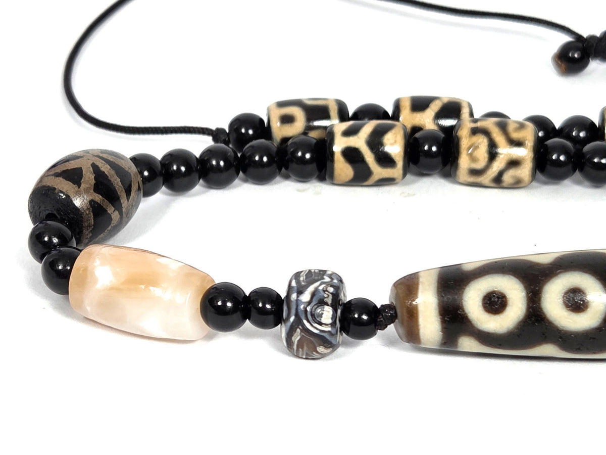 Seven-eye dzi bead necklace, brown agate, white eye motifs, aged patina, with patterned barrel beads and black onyx spacers