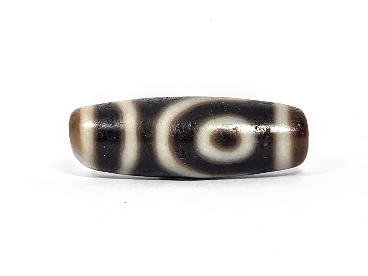 Two-eye dzi bead, black and cream agate with natural striping and eye motifs, polished surface, 34.3mm