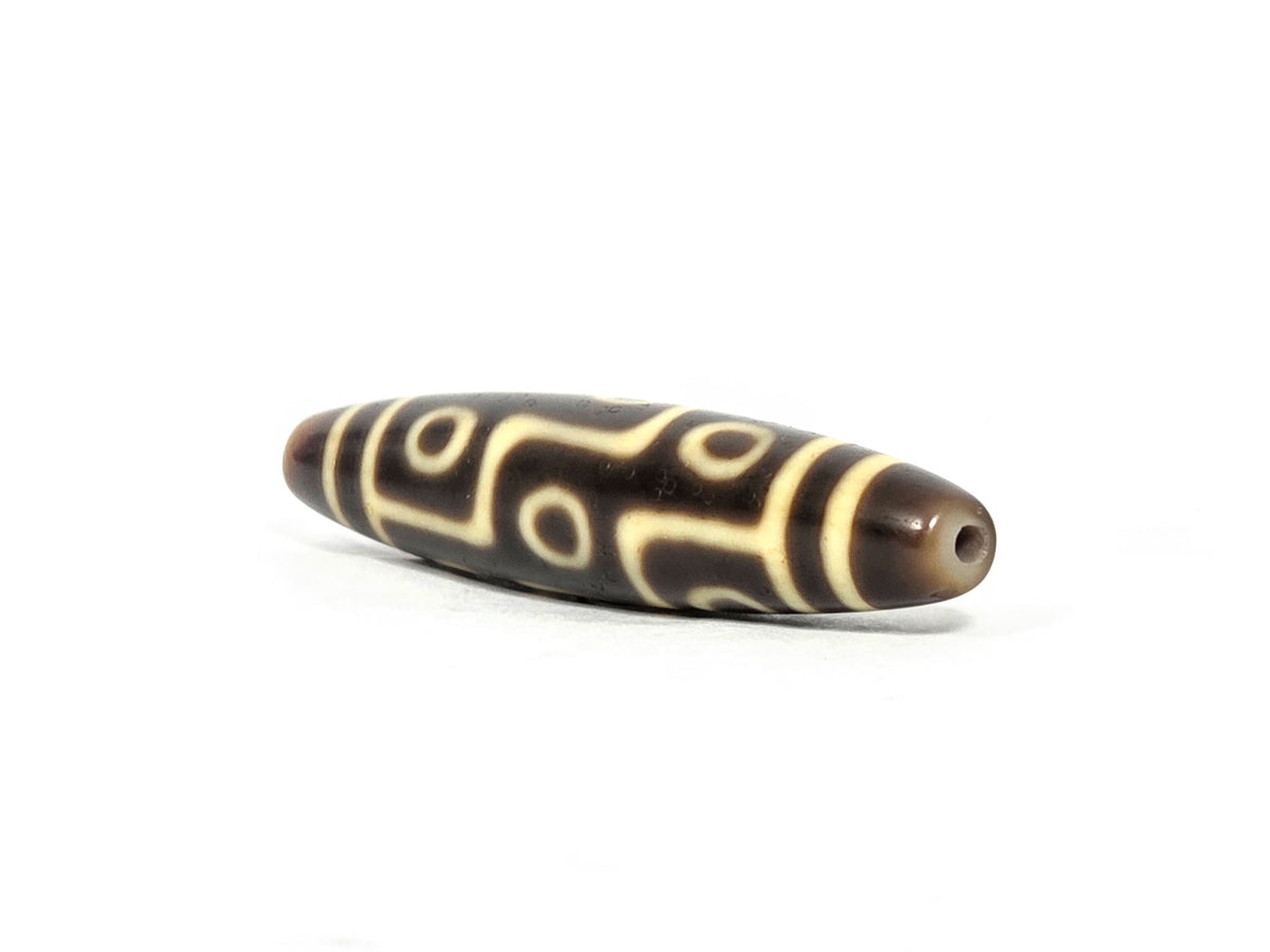 At-071126-9E8 rounded drill-hole end, warm honey-golden end cap, small centred hole, motif visible on body, unretouched