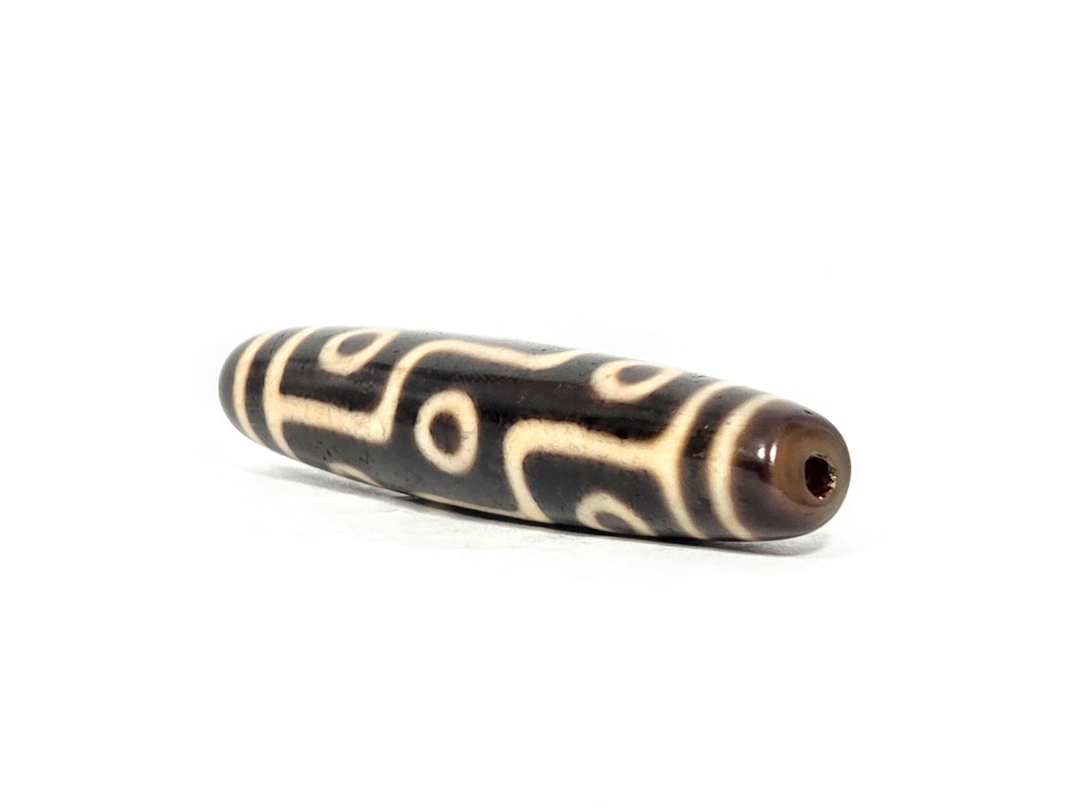 At-070826-9E antique nine eye dzi bead angled view left drill end warm reddish-brown end cap profile unretouched