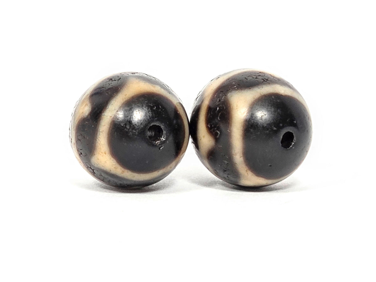 V-060826-DWP2 opposite end pair, diamond lozenge resolution visible, pitch-black ground, sandy-cream, unretouched