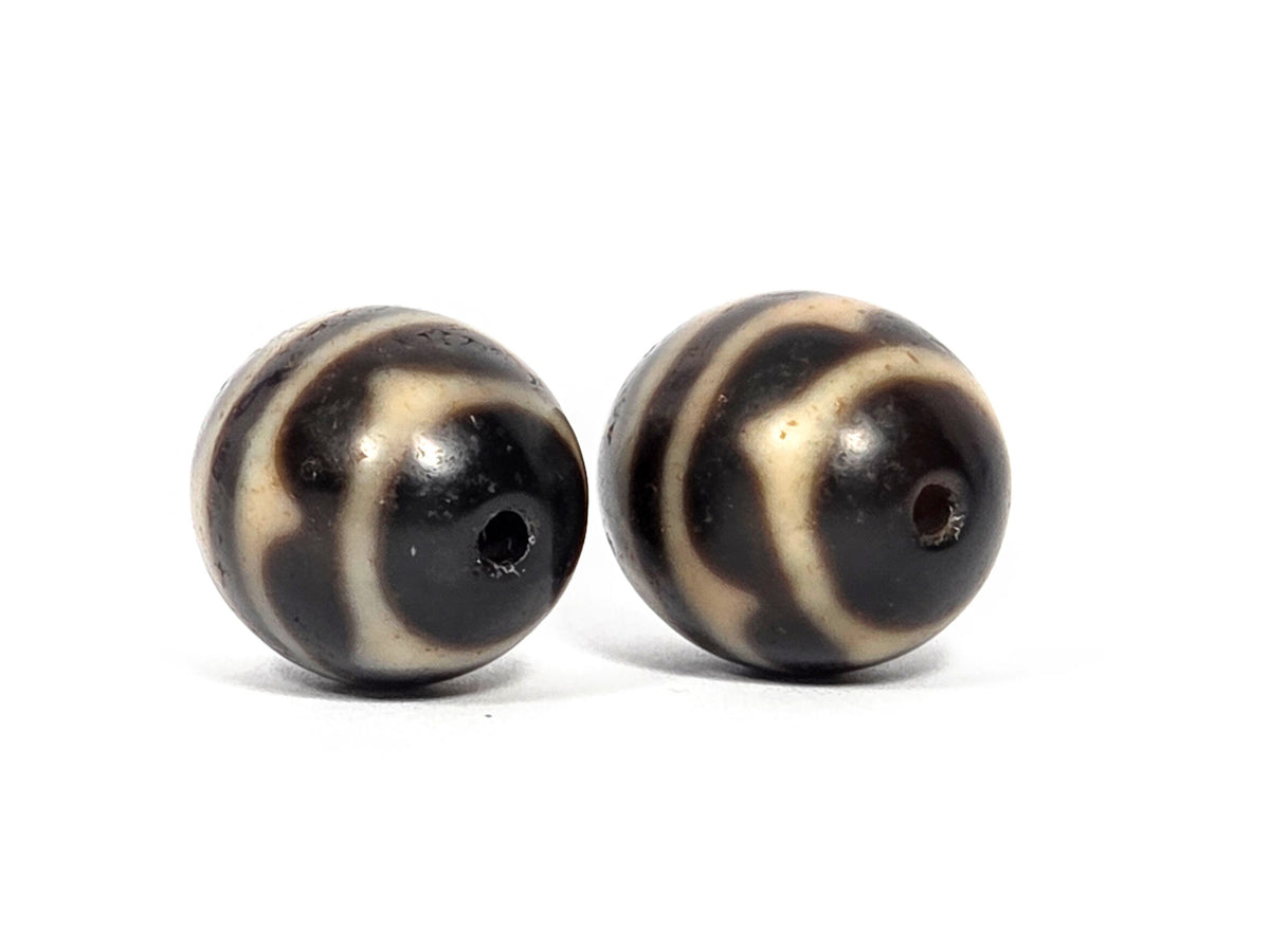 V-071426-DWP3 Double Wave pair drill-end angle B — opposite pole both beads, cream arc sweep, dark ground, unretouched.
