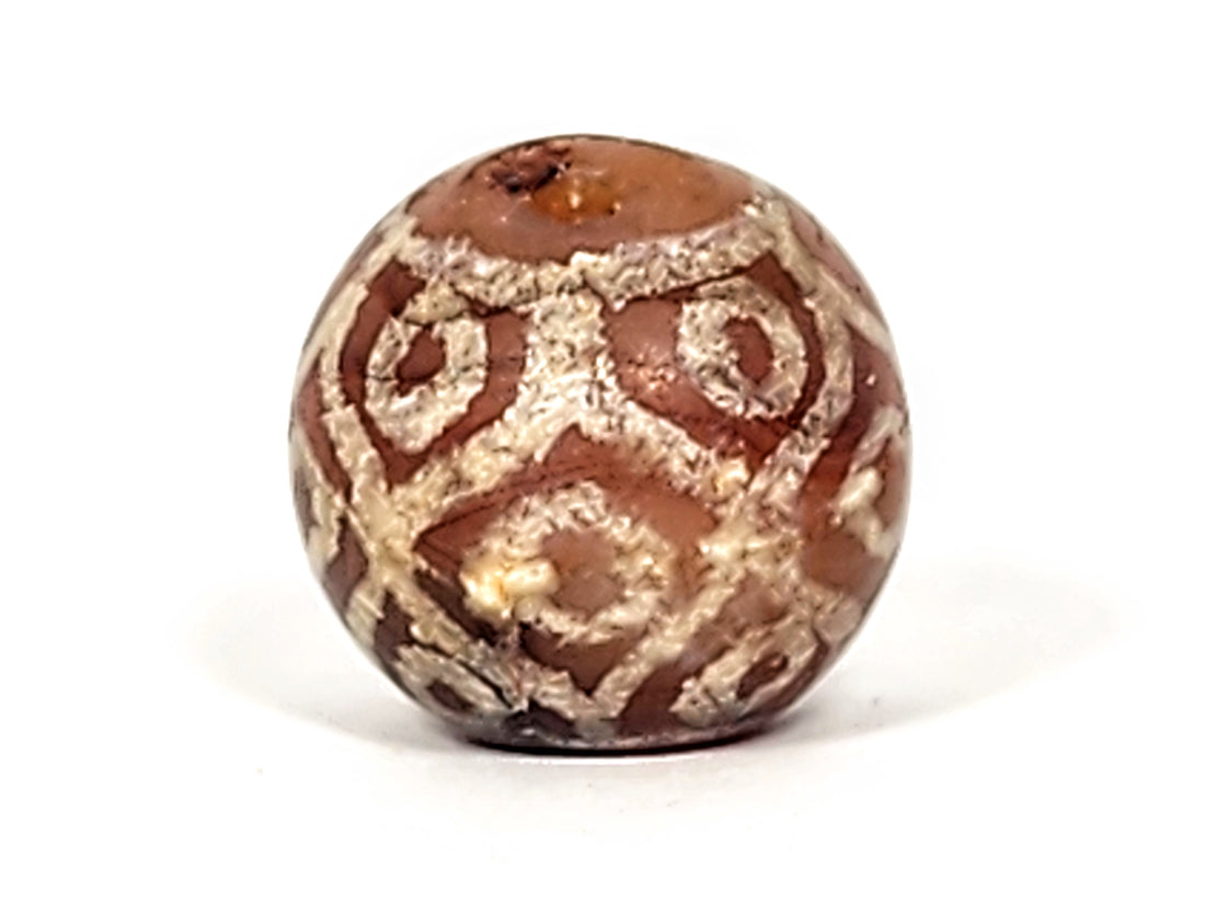 Ancient carnelian dzi bead showing warm orange-red natural agate with traditional etched motif — Pema Raka dzi from Himalayan collection