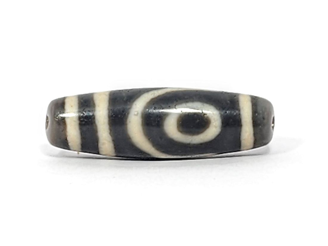Ancient Tibetan two-eye dzi bead — genuine dark agate with cream white eye motifs, showing natural surface patina and original etching