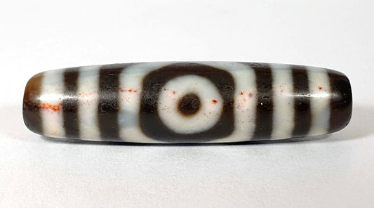 Antique Tibetan three eye dzi bead with extreme cinnabar bloodspots, red inclusions scattered across the cream agate bands, dark brown ground, unretouched photo by Ancient Dzi Shop