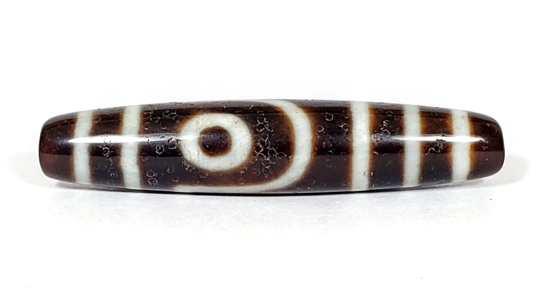 Vintage 1980s Taiwan dzi bead with a cream eye, crescent arc, and cream stripes on dark brown agate, showing light surface wear, unretouched photo by Ancient Dzi Shop