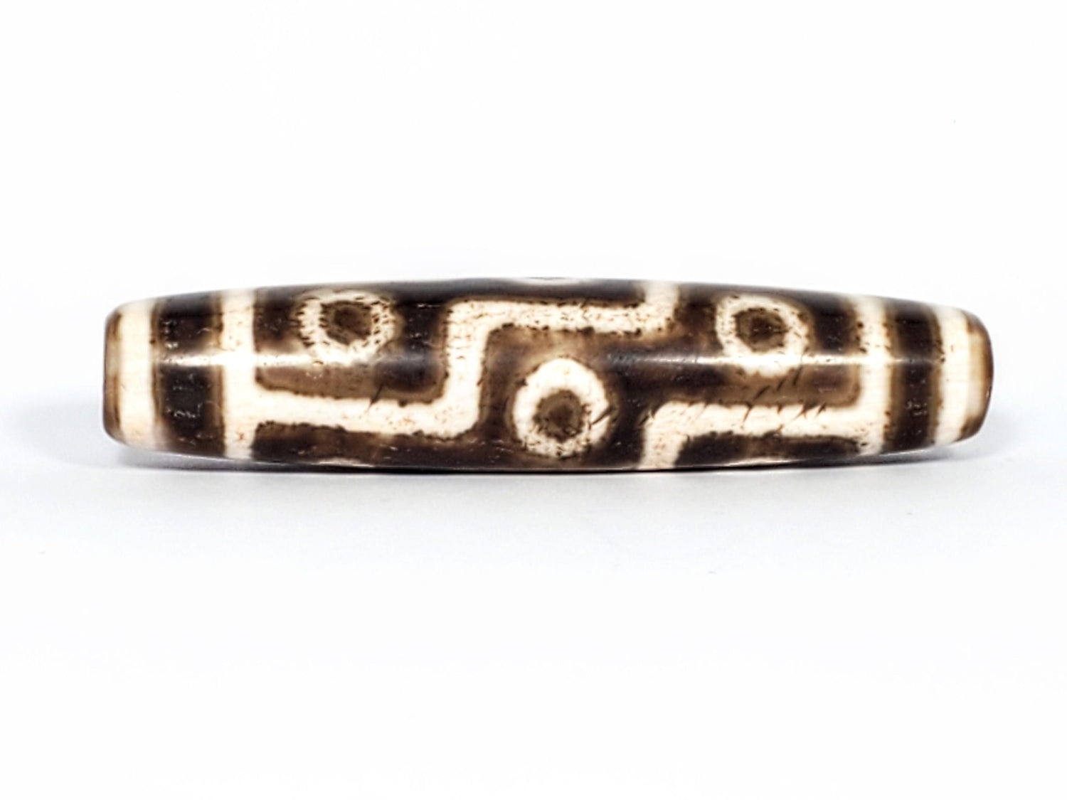 Rare Qing Dynasty nine eye dzi bead, dark brown agate with cream etched eye rings and S-curve connectors, natural patina visible in grooves, white end caps, unretouched — Ancient Dzi Shop
