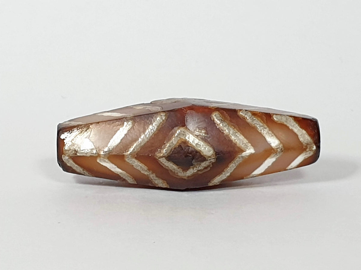 Ancient hexagonal carnelian dzi bead, three-eye tiger stripe motif, etched white chevron pattern, amber brown agate, aged patina
