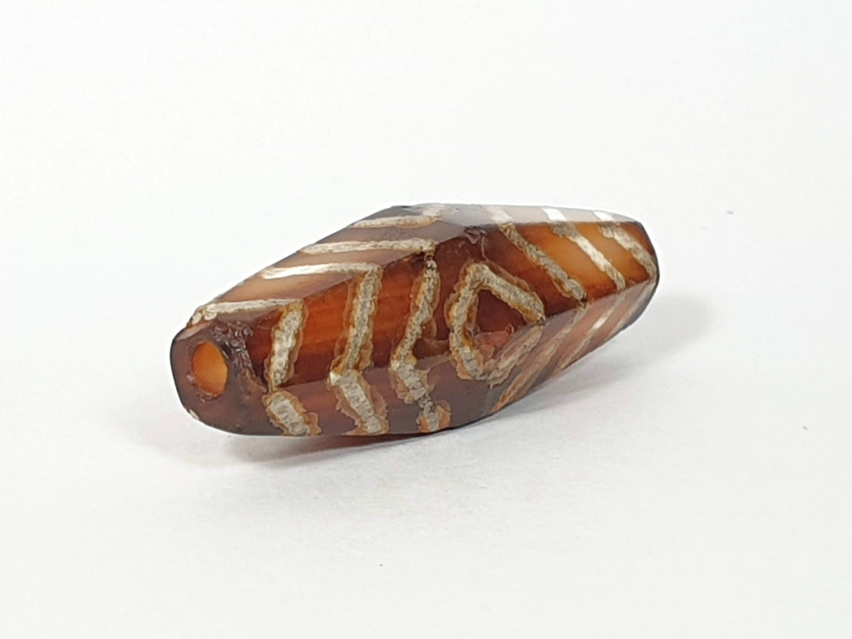 Ancient carnelian dzi bead, hexagonal, three-eye tiger stripe motif, brown agate, white etched pattern, visible drill hole, aged patina