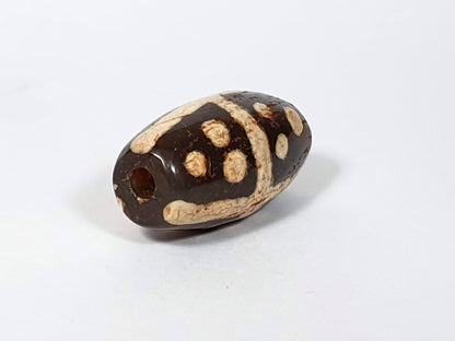Ancient eighteen star motif agate dzi bead with tan dot patterns on dark brown surface and visible drill hole