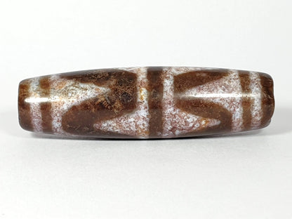 N-062126-DW dzi bead, angled view of rounded end, no visible drill hole this side, unretouched