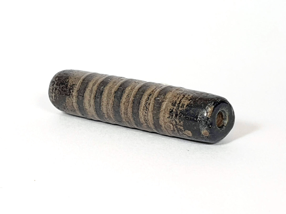 Ac-080420-19SChung, Bead B left end drill hole, encrusted end face, narrow stripe bands visible on cylindrical body, unretouched