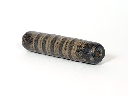 Ac-080420-19SChung, Bead B left end drill hole, encrusted end face, narrow stripe bands visible on cylindrical body, unretouched