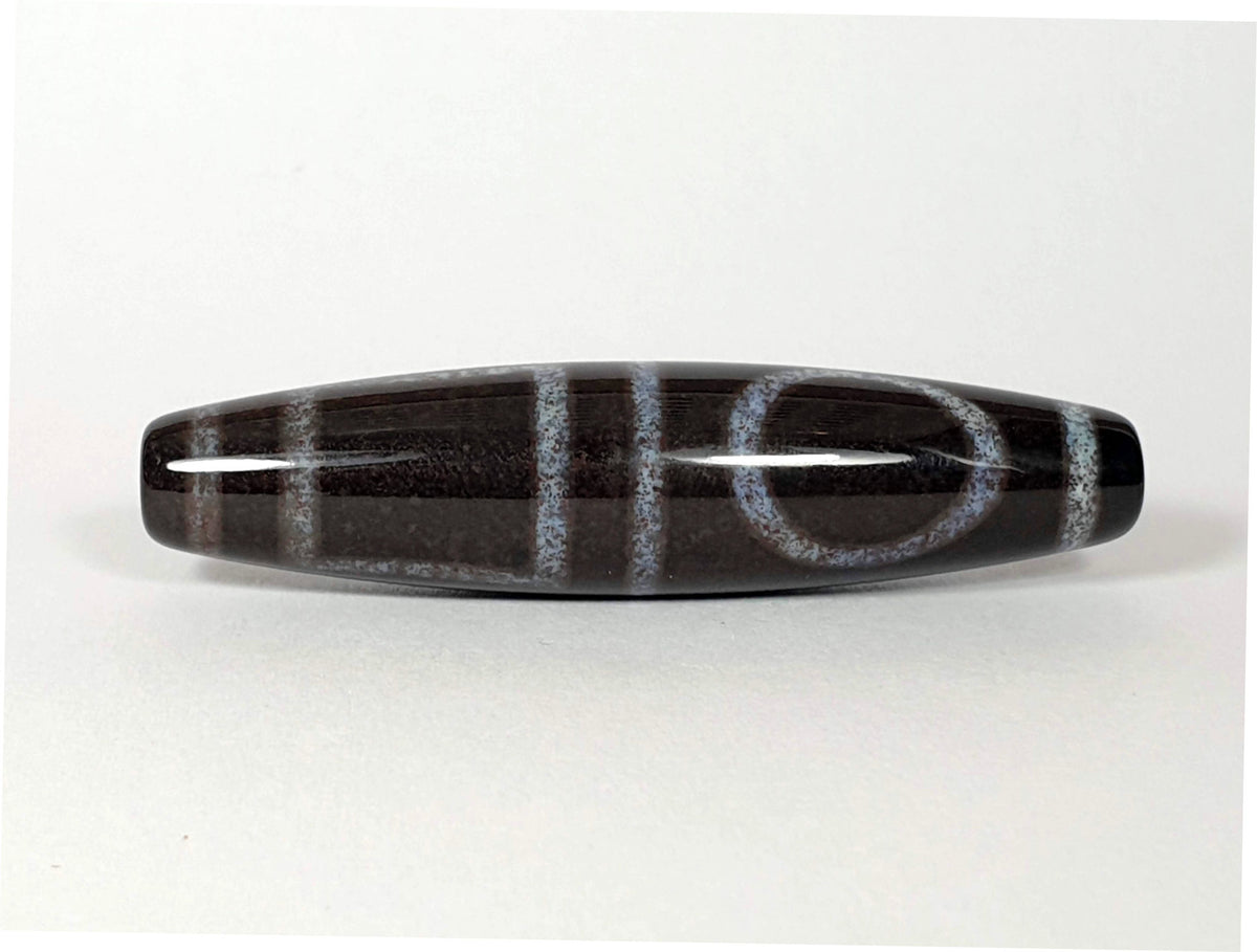 N-062126-HE dzi bead, angled view of opposite drilled end, full motif visible, unretouched