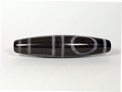 N-062126-HE dzi bead, angled view of opposite drilled end, full motif visible, unretouched