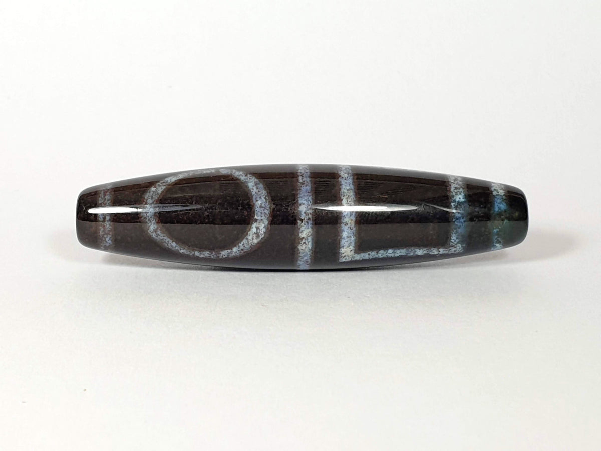 N-062126-HE dzi bead, three-quarter angle showing drilled end, unretouched