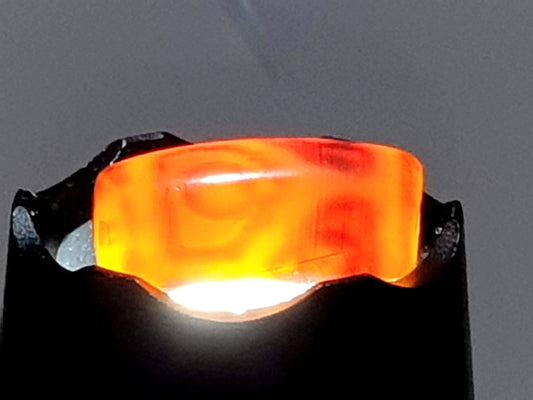 Antique six-eye lotus dzi bead, translucent orange-red agate, backlit revealing swirling patterns and natural inclusions, worn patina