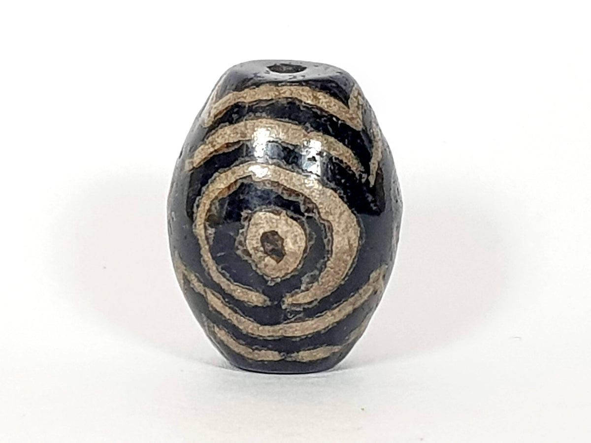 Ancient triple heaven's gate dzi bead, black agate, cream spiral motif, visible drill hole, aged patina, oval barrel shape