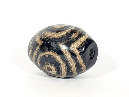 Ancient triple heaven's gate motif dzi bead, black agate, tan etched spiral patterns, visible drill hole, aged patina surface