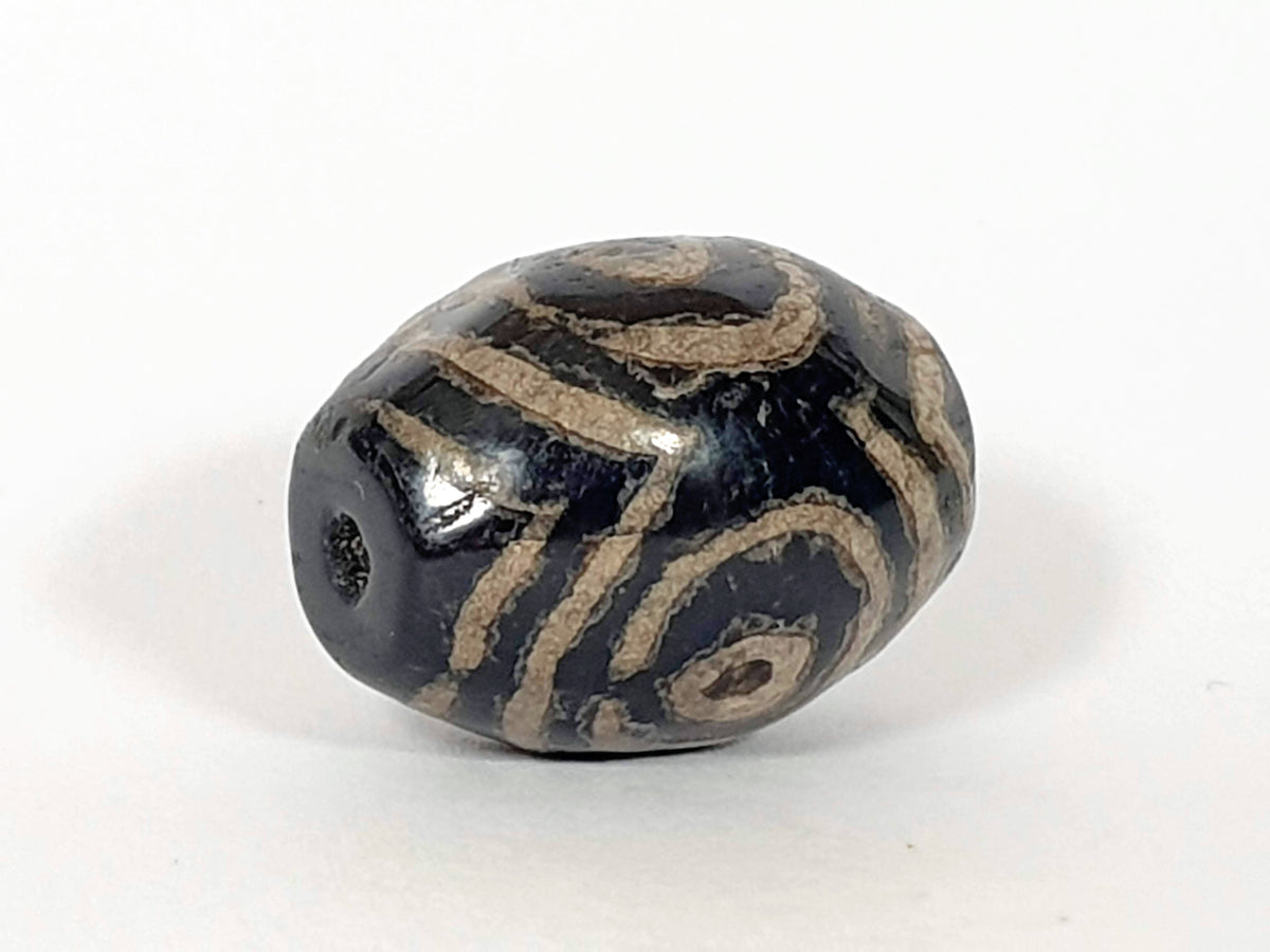 Ancient triple heaven's gate dzi bead, dark agate, cream etched swirl motifs, visible drill hole, aged patina surface