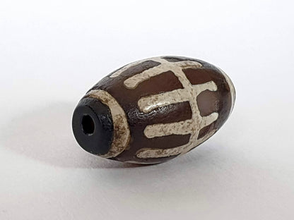 Ac-062426-SR Bead A angled view near-black end cap zone small drill hole sun ray motif unretouched