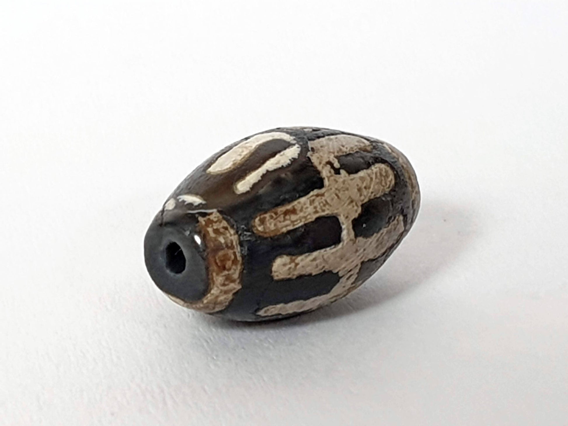 Ac-062426-SR Bead B angled view deeply saturated near-black ground raised mineralised sun ray motif unretouched