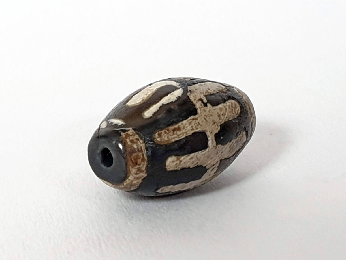 Ancient sun ray motif agate dzi bead with natural cream and black striping, visible drill hole, 1200-1500 years old