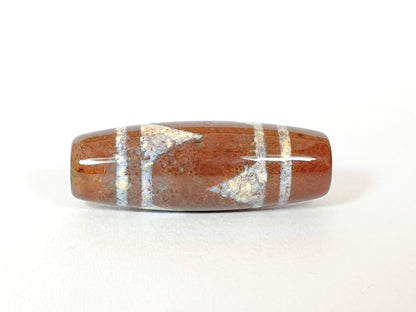 N-062426-TTBS Bead A tiger tooth dzi angled view warm reddish-brown ground sandy-cream tooth motif drill hole unretouched