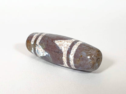 Tiger Tooth Agate Dzi Bead with white stripes and bloodspots, showing natural patina and drill hole