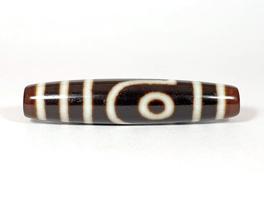 V-070226-2E2 vintage two eye dzi bead, front view, brown to black ground, 54.5×11.9mm, unretouched.