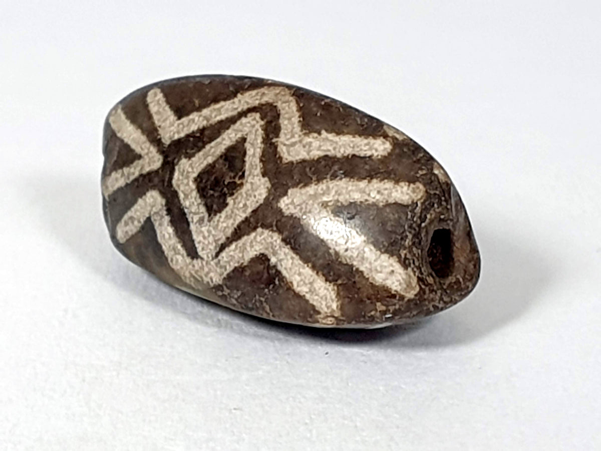 Antique triangular dzi bead, dark agate, etched white diamond eye tiger tooth motif, visible drill hole, aged patina surface