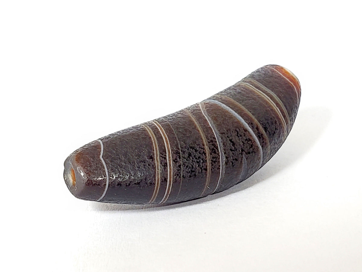 Bow-shaped natural banded agate dzi bead with earth-tone striping and polished surface