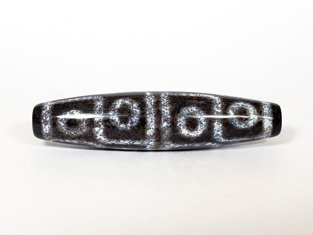 N-062126-12E-2 dzi bead, close side profile, visible surface speckling, unretouched