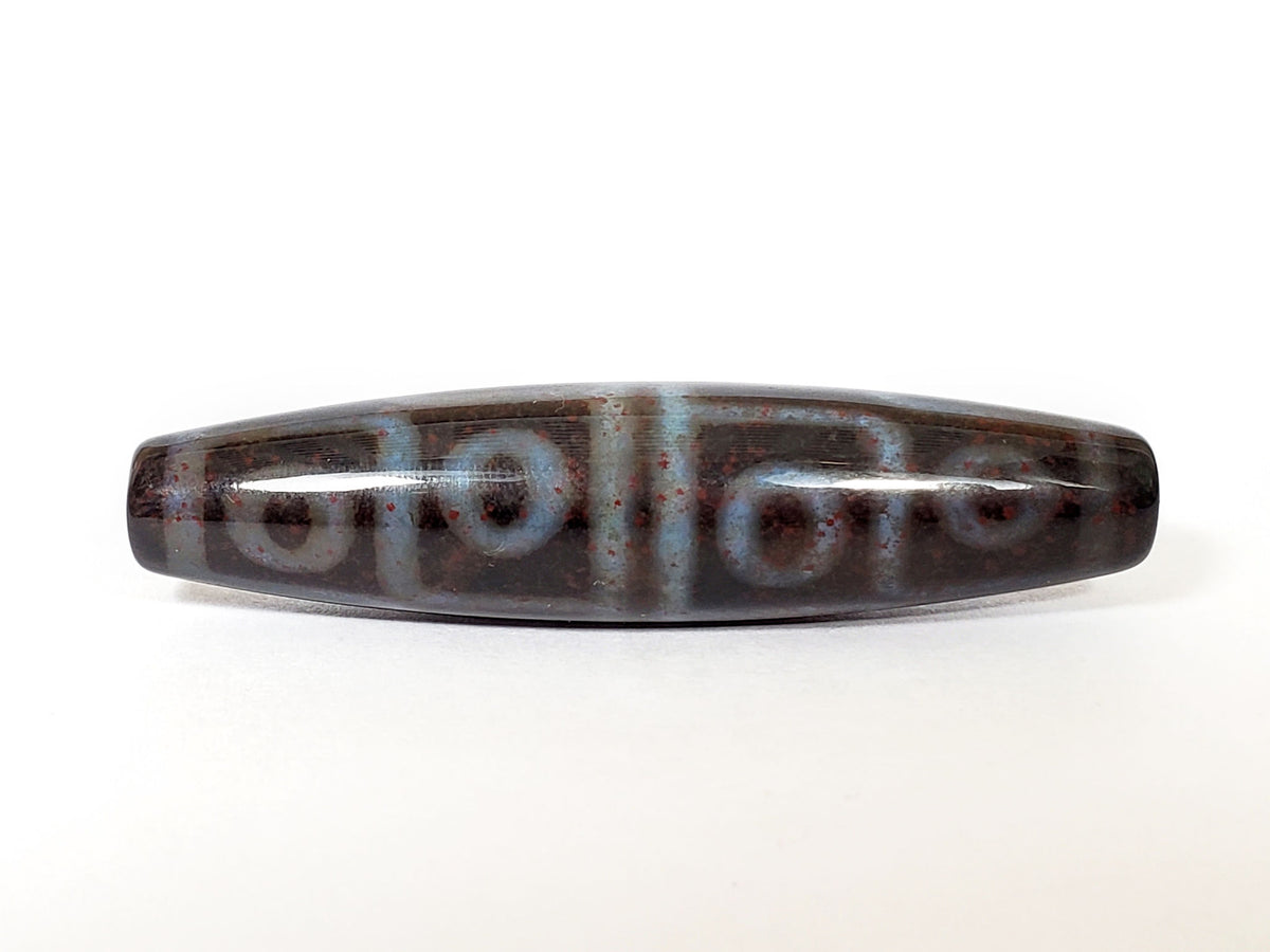 N-062126-12E-1 dzi bead, three-quarter angle showing drilled end, unretouched