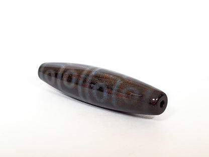 Twelve eye motif dzi bead with red bloodspots, dark brown agate, polished surface, drilled hole visible