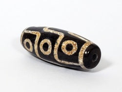 Nine-eye dzi bead with natural agate patterns, black and cream striping, and visible bloodspots