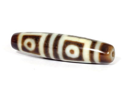 V-070226-4E dzi bead, full-length diagonal view, dark brown motif on cream ground, unretouched.