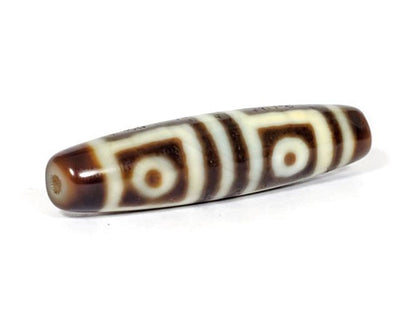V-070226-4E dzi bead, diagonal view showing drill hole, dark brown motif, unretouched photo.