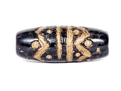 Ancient black agate dzi bead with wave and star motifs, cream etched patterns, aged patina, oval barrel shape, antique finish