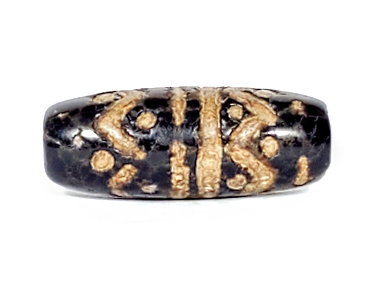 Ancient black agate dzi bead with wave and star motifs, cream etched patterns, aged patina, oval barrel shape, antique Tibetan