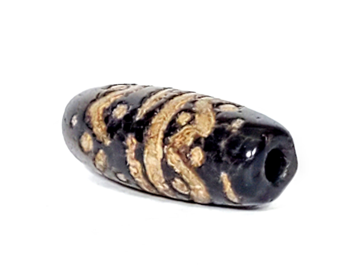Ancient wave motif dzi bead, black agate with golden tan stripe pattern, visible drill hole, aged patina texture