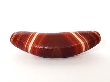 Bow-shaped natural banded agate dzi bead with white striping and deep red-brown coloring